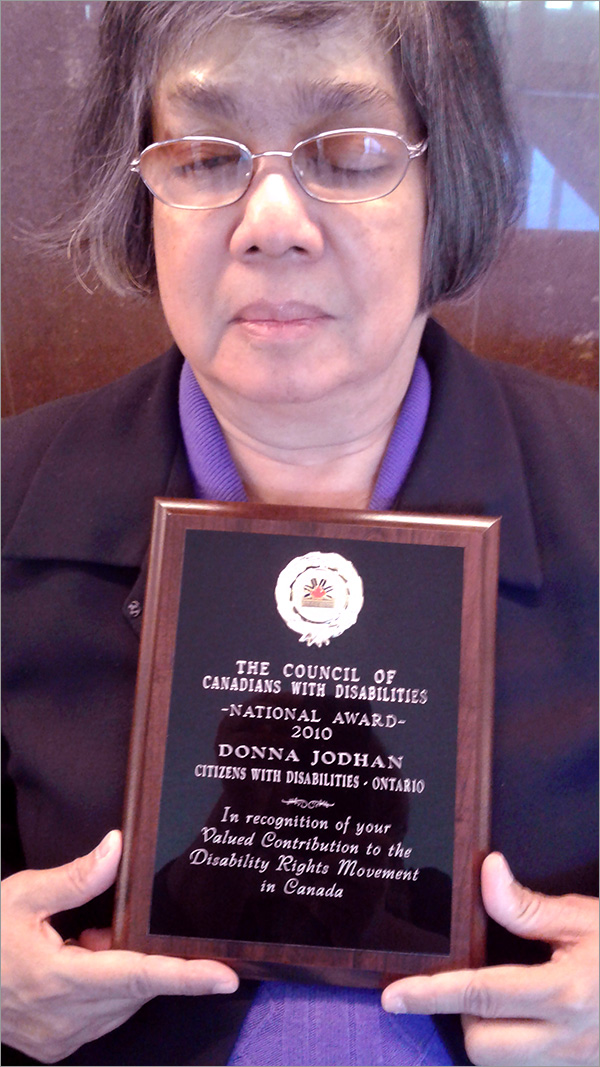 Photo of Donna Jodhan holding the 2010 National Award  presented by The Council of Canadians with Disabilities for Recognition of Valued Contribution to the Disability Rights Movement in Canada.